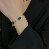 Gold bracelet with green stones on a wrist 
